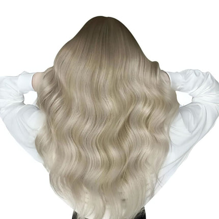 Extensions invisibles longues ondulées en cheveux naturels blond clair.