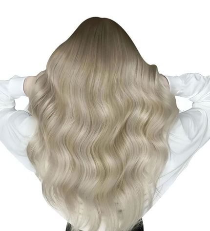 Extensions invisibles longues ondulées en cheveux naturels blond clair.